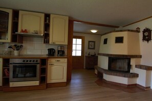 A kitchen with wooden cabinets, a built-in oven, and a fireplace. - Bungalow with 2 bedrooms (Reinhardtsdorf-Schöna)