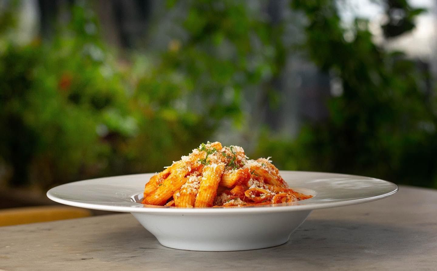 Ein weißer Teller mit Pasta auf einem Tisch.