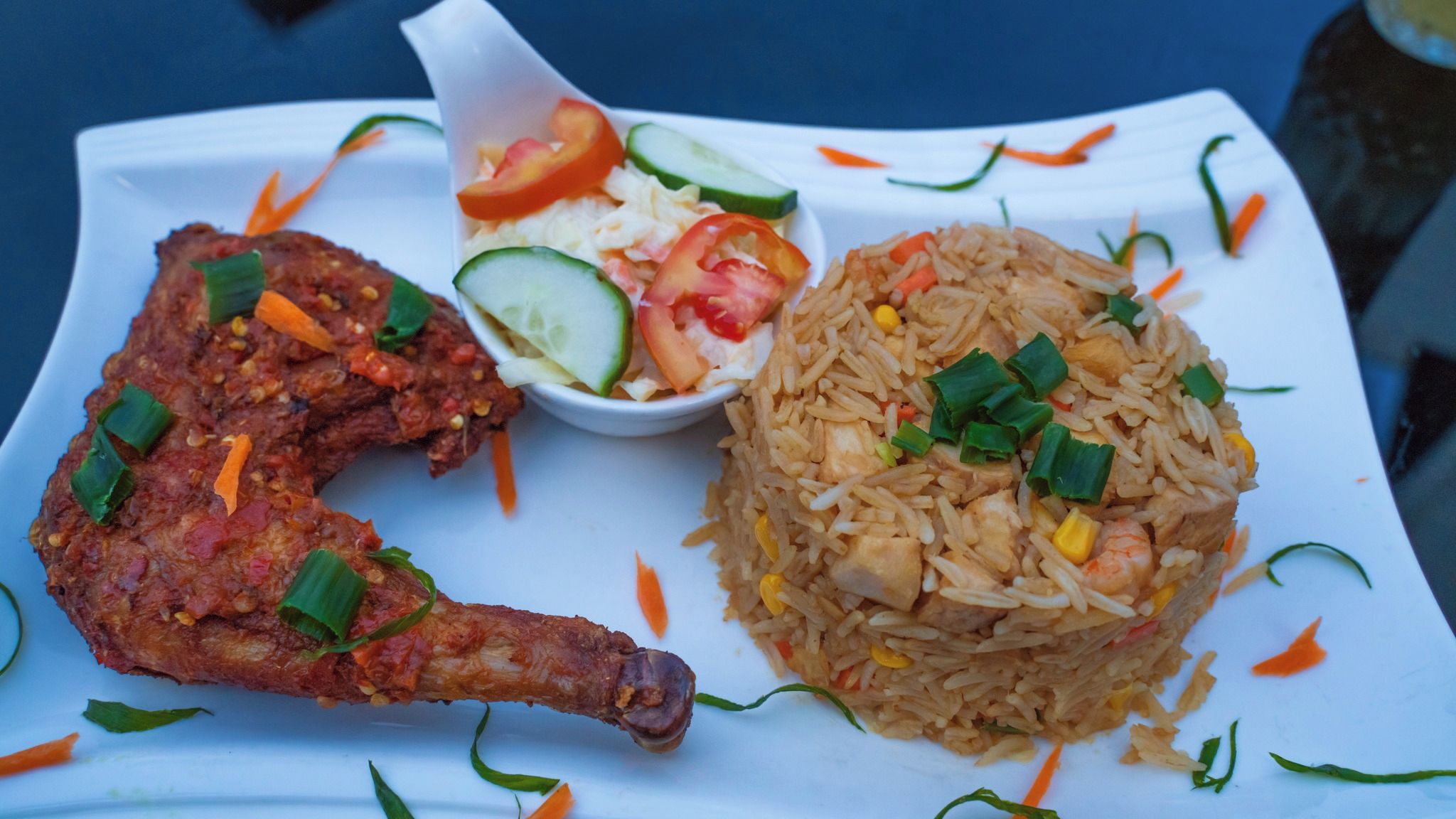 A plate with fried chicken, fried rice, and a side salad.