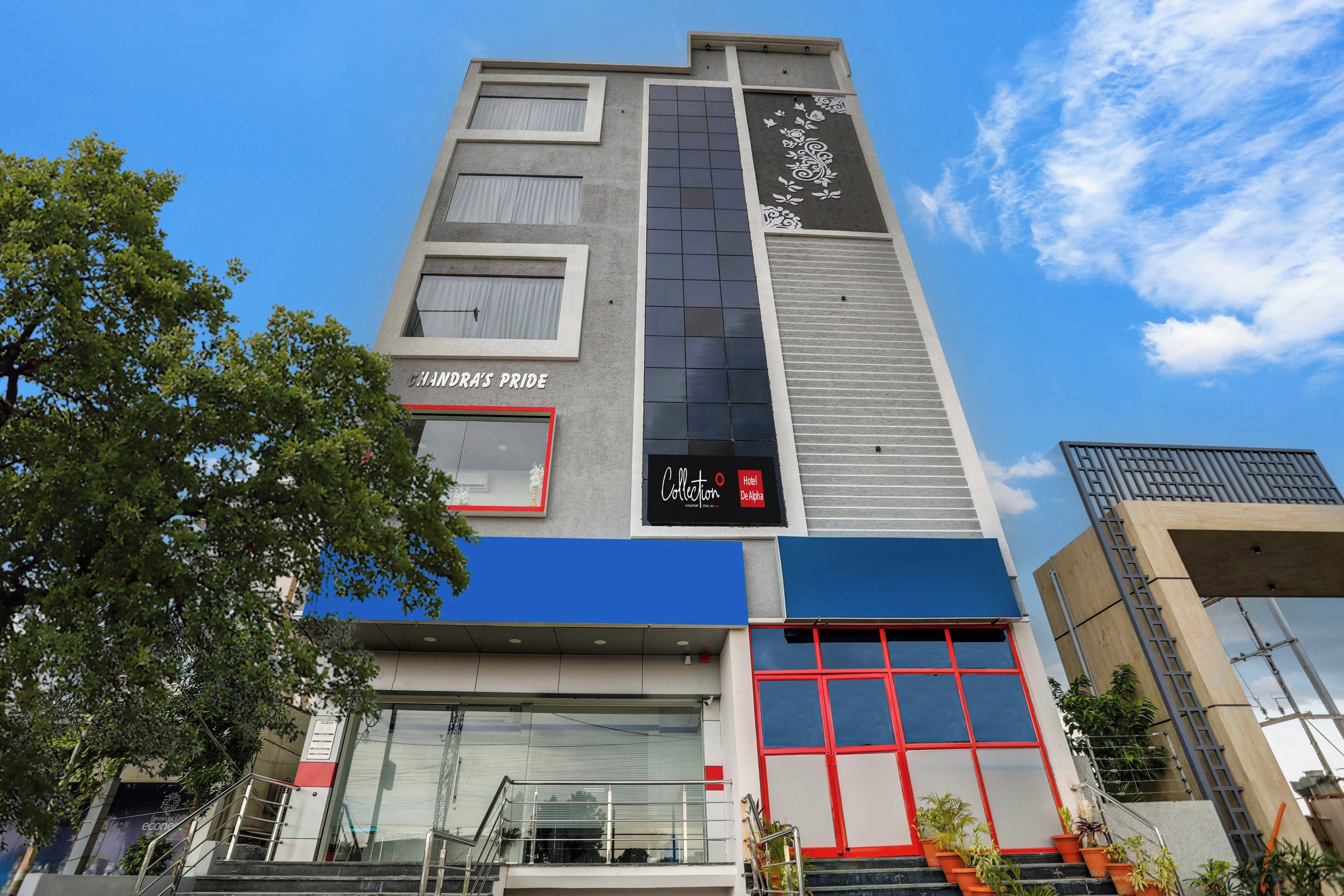 Un edificio de hotel con un cartel llamativo que dice 'CHANDRA'S PRIDE' y un cartel más pequeño para 'Hotel De Alpha Collection'.