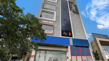 A modern hotel building with a prominent sign for 'Chandra's Pride' and a 'Collection Hotel De Alpha' sign.