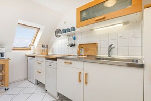 A modern kitchen with white cabinets, a wooden countertop, a built-in oven, and a window above the sink. - Holiday apartment in Binz with swimming pool (Binz)