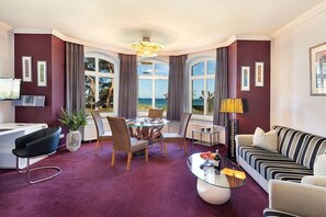 A hotel room with a dining area, a sofa, a coffee table, and a view of the sea. - Bellevue in the Villa Glückspilz (Binz)