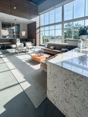 A modern living room with a large window, a marble countertop, and a seating area with a sofa and chairs. - Altitude Apartments - Atlanta City (Atlanta)