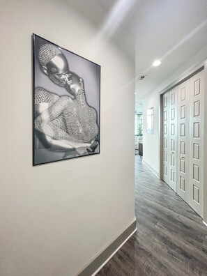A hallway with a framed artwork on the wall and a door with a panel design. - Altitude Apartments - Atlanta City (Atlanta)