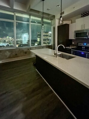 Eine moderne Küche mit einem großen Fenster, einer eingebauten Spüle und Edelstahlgeräten.