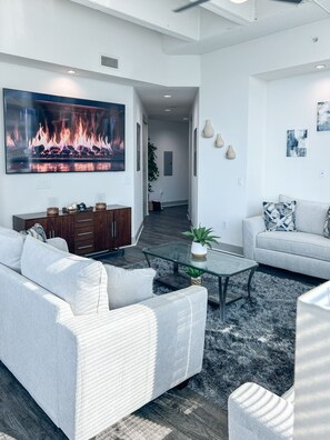A modern living room with a large flat-screen TV, a glass coffee table, and two sofas. - Altitude Apartments - Atlanta City (Atlanta)