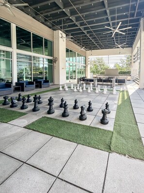 An outdoor area with a chessboard set up on a paved surface, surrounded by seating and a covered section with tables and chairs. - Altitude Apartments - Atlanta City (Atlanta)