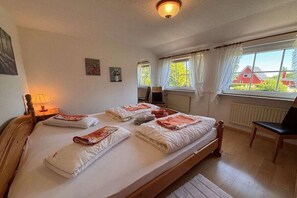 Een kamer met een bed, een stoel, een lamp en een raam met gordijnen.
