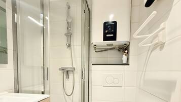 A modern bathroom with a glass-enclosed shower, a white toilet, and a sink with wooden cabinetry.