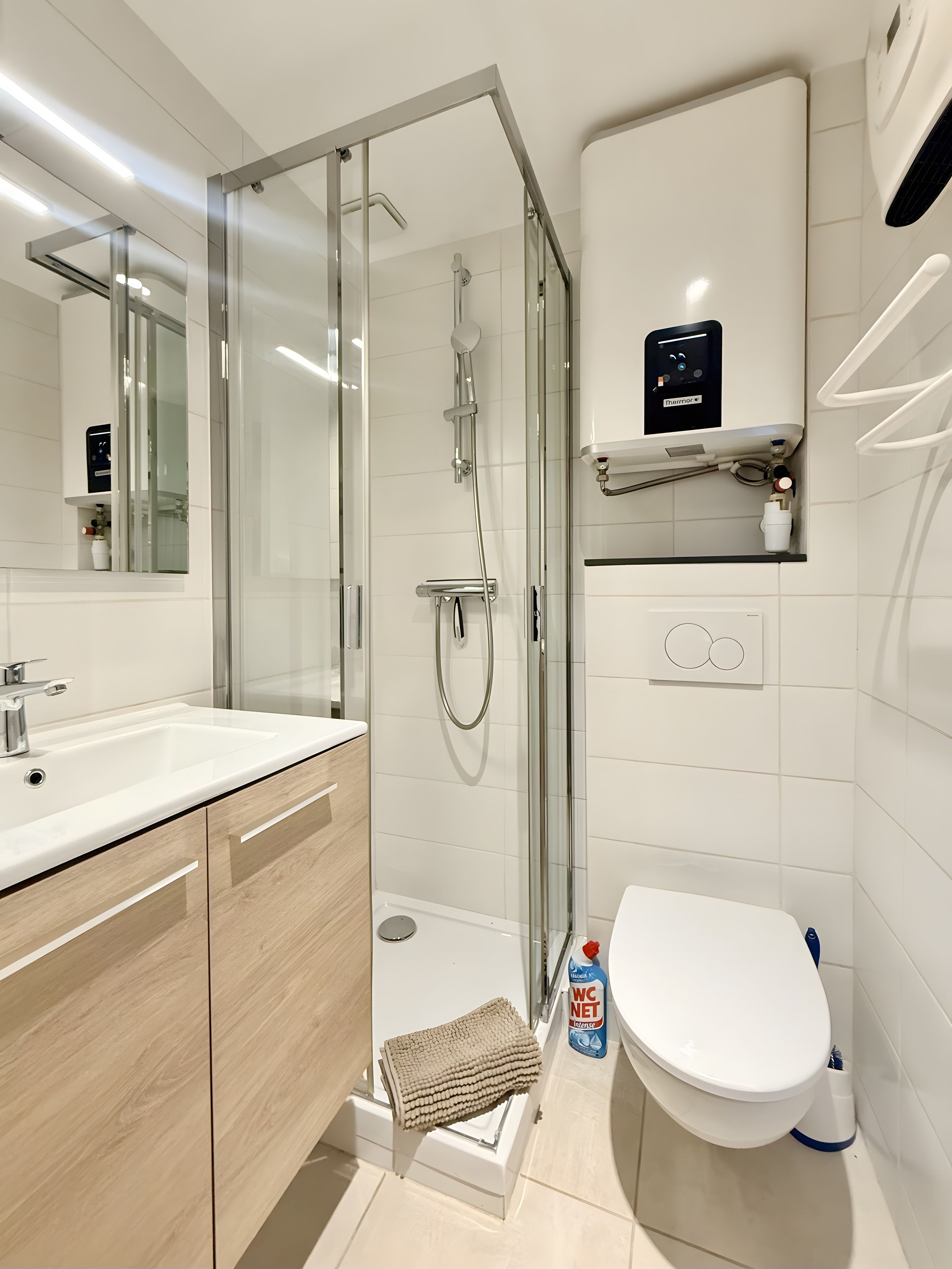 A modern bathroom with a glass-enclosed shower, a white sink, and a toilet.