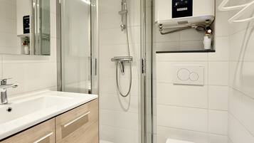 A modern bathroom with a glass-enclosed shower, a white sink, and a toilet.