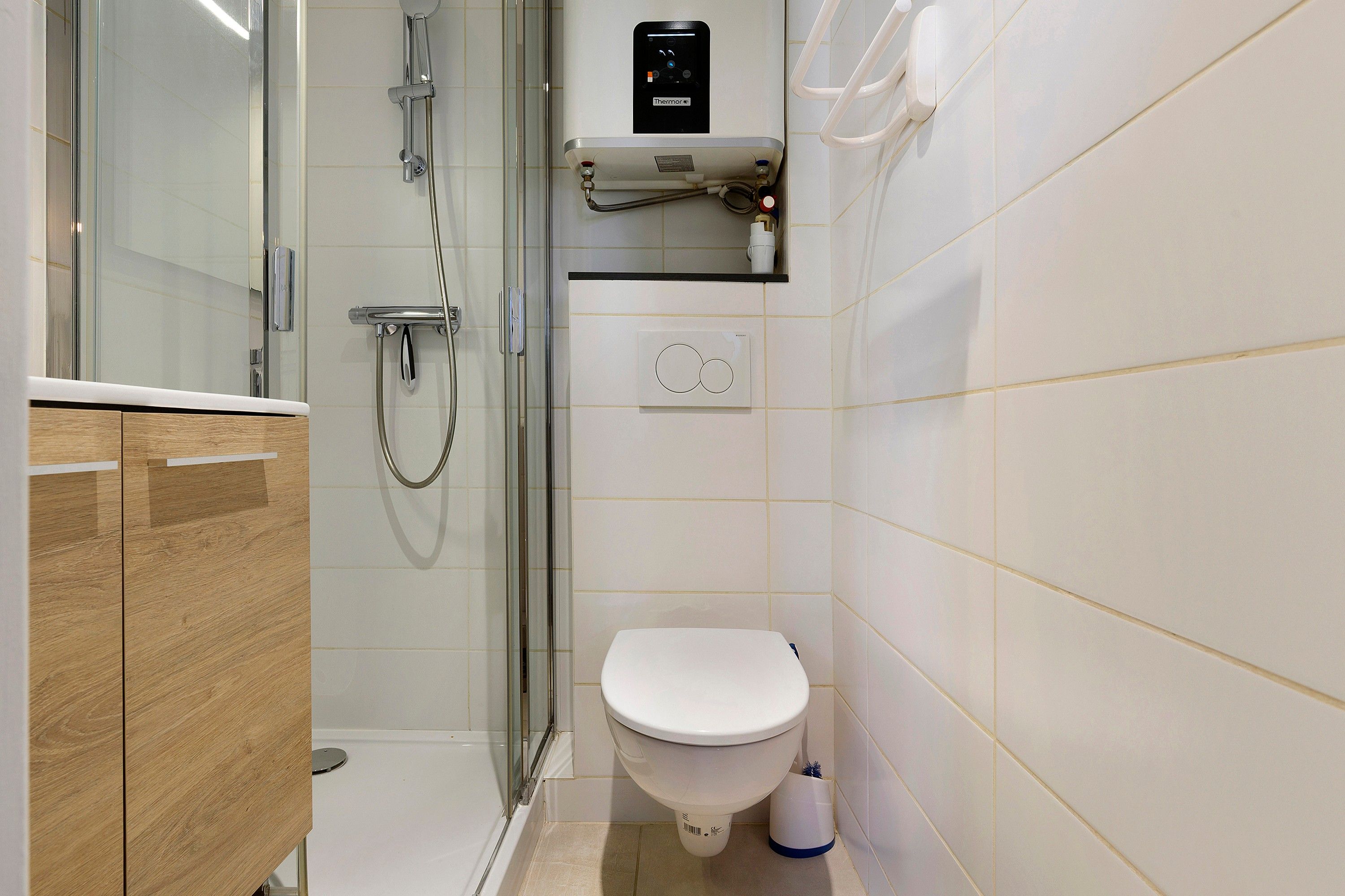 Une salle de bain moderne dotée d’une douche à parois de verre, de toilettes et d’un panneau de commande pour la douche.