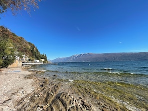 A lakeside view with rocky shores, a pier, and a building with a white facade. - D1MORA Nautilus - incredible lakeside location (Lombardia)