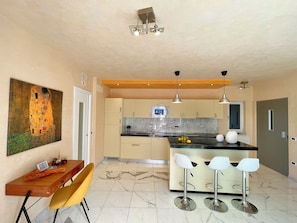 A modern kitchen with a marble countertop, two bar stools, and a dining table with chairs. - D1MORA Nautilus - incredible lakeside location (Lombardia)