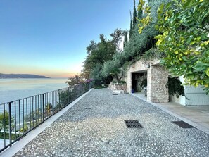 A paved walkway with a stone wall and a metal railing overlooking a body of water. - D1MORA Nautilus - incredible lakeside location (Lombardia)