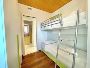 A bunk bed room with a wooden floor and a door leading to a bathroom. - D1MORA Nautilus - an incredible lakeside location (Lombardia)