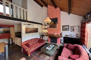 Una sala de estar con chimenea, un sofá, una mesa de centro y una lámpara colgante.