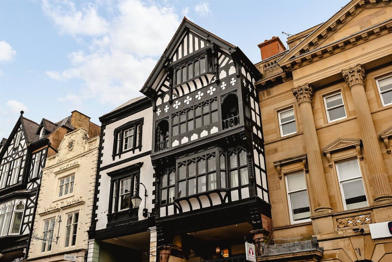 A row of traditional buildings with distinct architectural styles, including timber framing and classical columns.