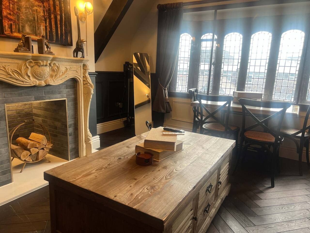 Una habitación con chimenea, una mesa de comedor con sillas y un ventanal de varios paneles.