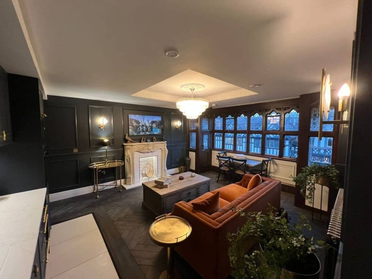 A modern living room with a fireplace, seating area, and large windows.