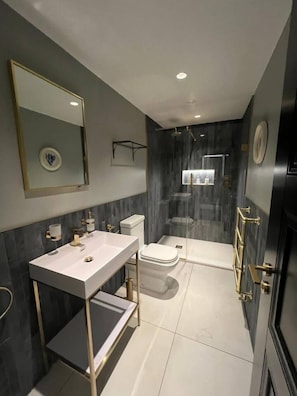 Un baño moderno con un espejo grande, un lavabo, inodoro y zona de ducha.