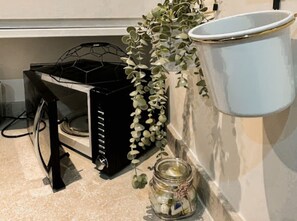 A kitchen area with a black appliance, a white container, a hanging plant, and a glass jar. - Mathew Street - City 1 BDR apt sleeps 6 (Merseyside)