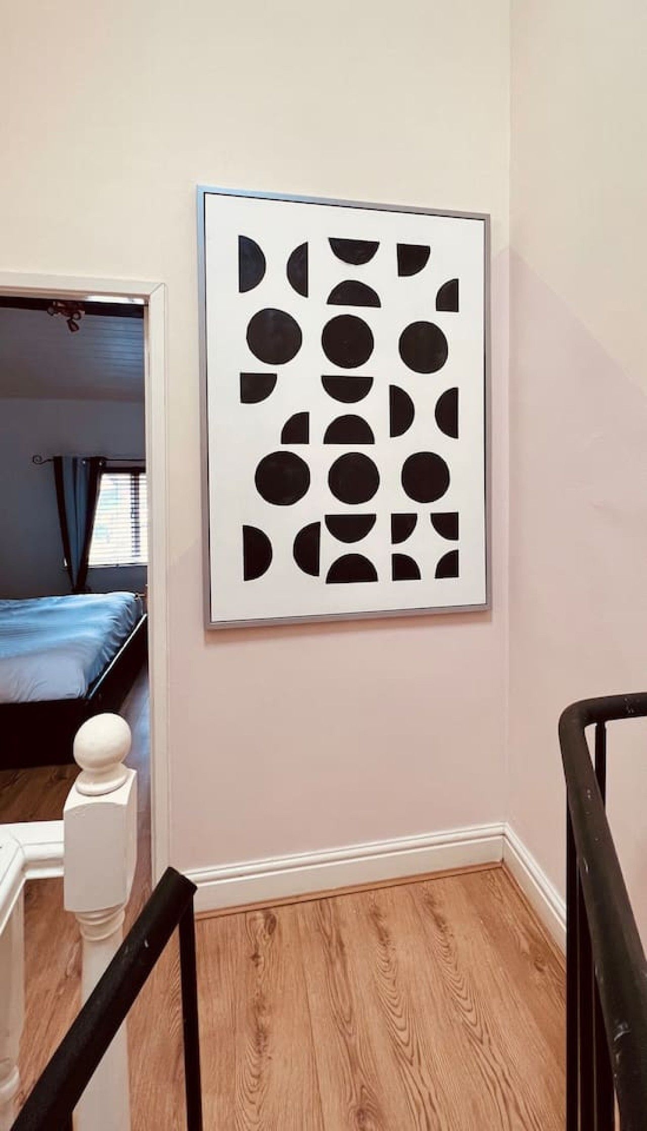 A room with a bed, a staircase, and a wall-mounted artwork.