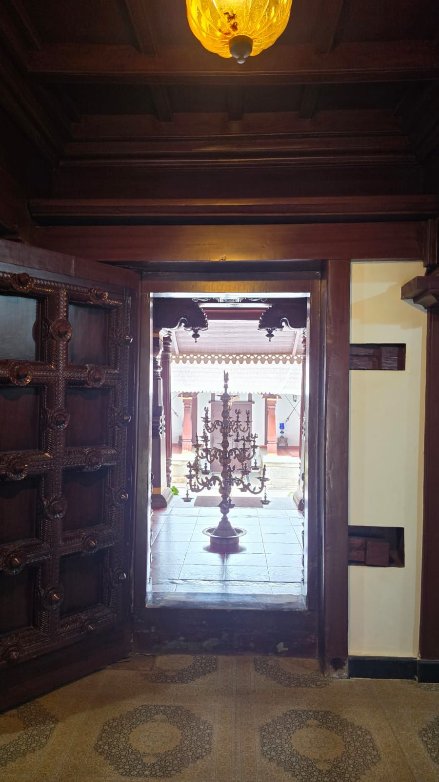 Una puerta de madera con tallas intrincadas que da a un patio con una reja de hierro decorativa y un pilar central.