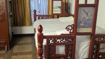 A traditional wooden bed with intricate carvings, a patterned carpet, and a window with curtains.