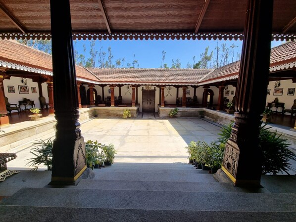 A courtyard with a central staircase, surrounded by covered areas with tiled roofs and columns.