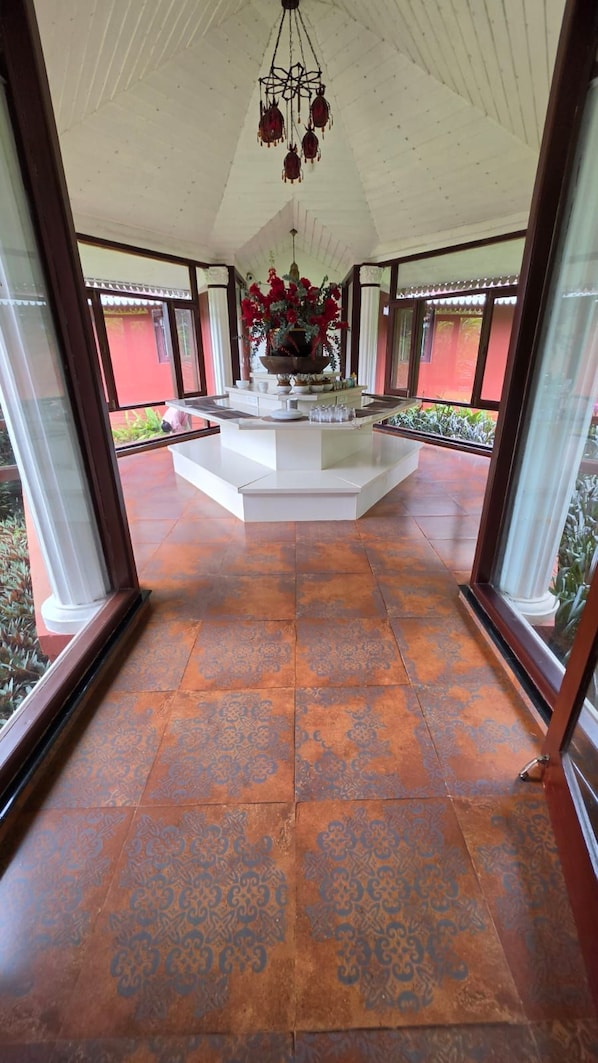 A spacious, sunlit interior with a central island, large windows, and patterned floor tiles.