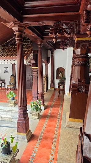 A traditional wooden interior with ornate columns and a tiled floor.