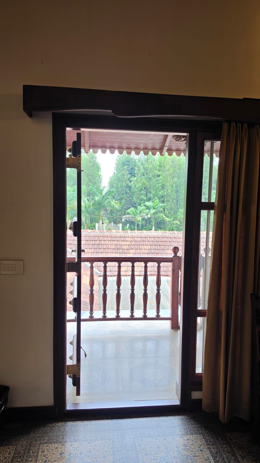 Puerta abierta que da a un balcón con vistas a una zona residencial y árboles.