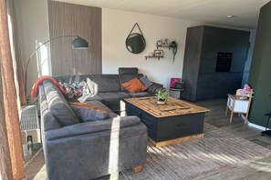 Ein modernes Wohnzimmer mit einem Ecksofa, einem Couchtisch und einem Kamin.
