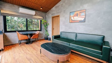 A modern interior with a wooden ceiling, a green sofa, a round coffee table, and a dining area with a table and chairs.