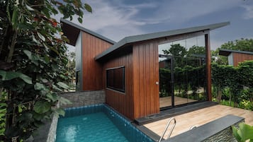 A modern outdoor pool area with a wooden deck and a glass-enclosed patio.