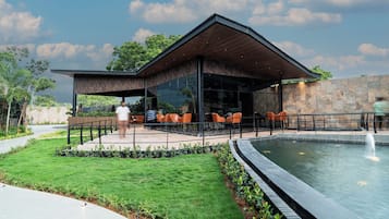 Et moderne udendørs loungeområde med swimmingpool, siddepladser og en overdækket terrasse.