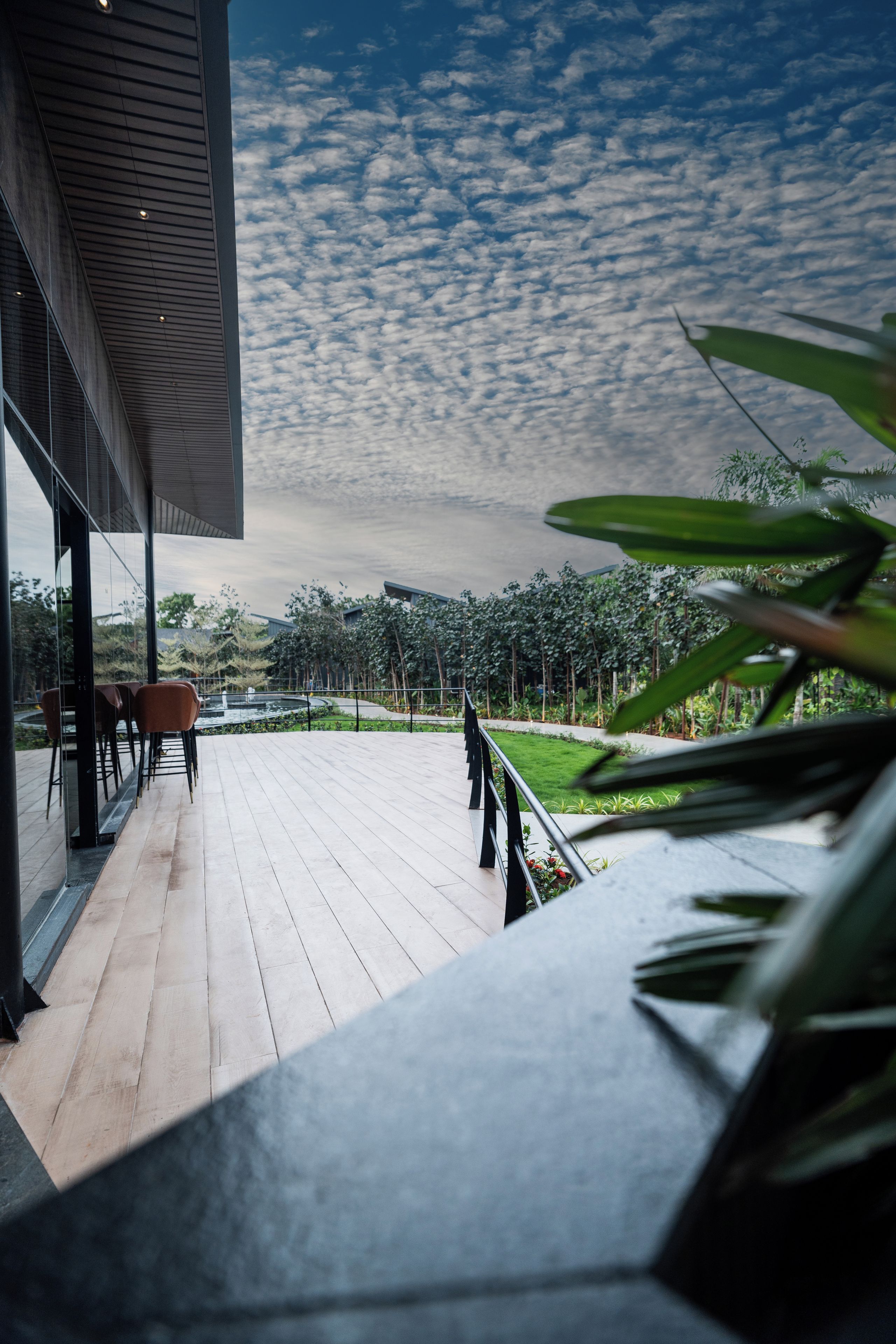 Eine moderne Terrassenanlage mit Blick auf einen Garten und einen bewölkten Himmel.