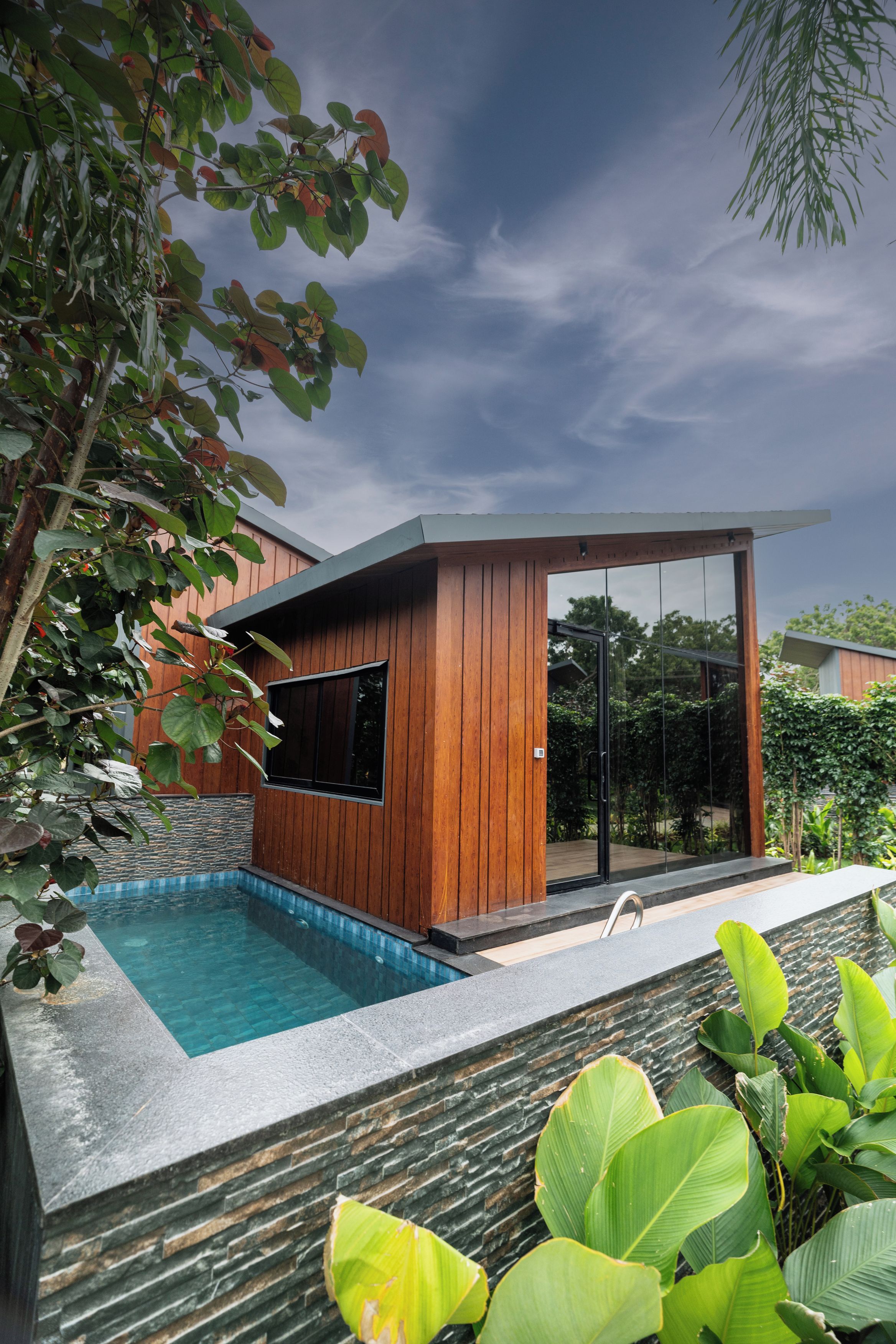 A modern house with a swimming pool, wooden exterior, and glass doors.