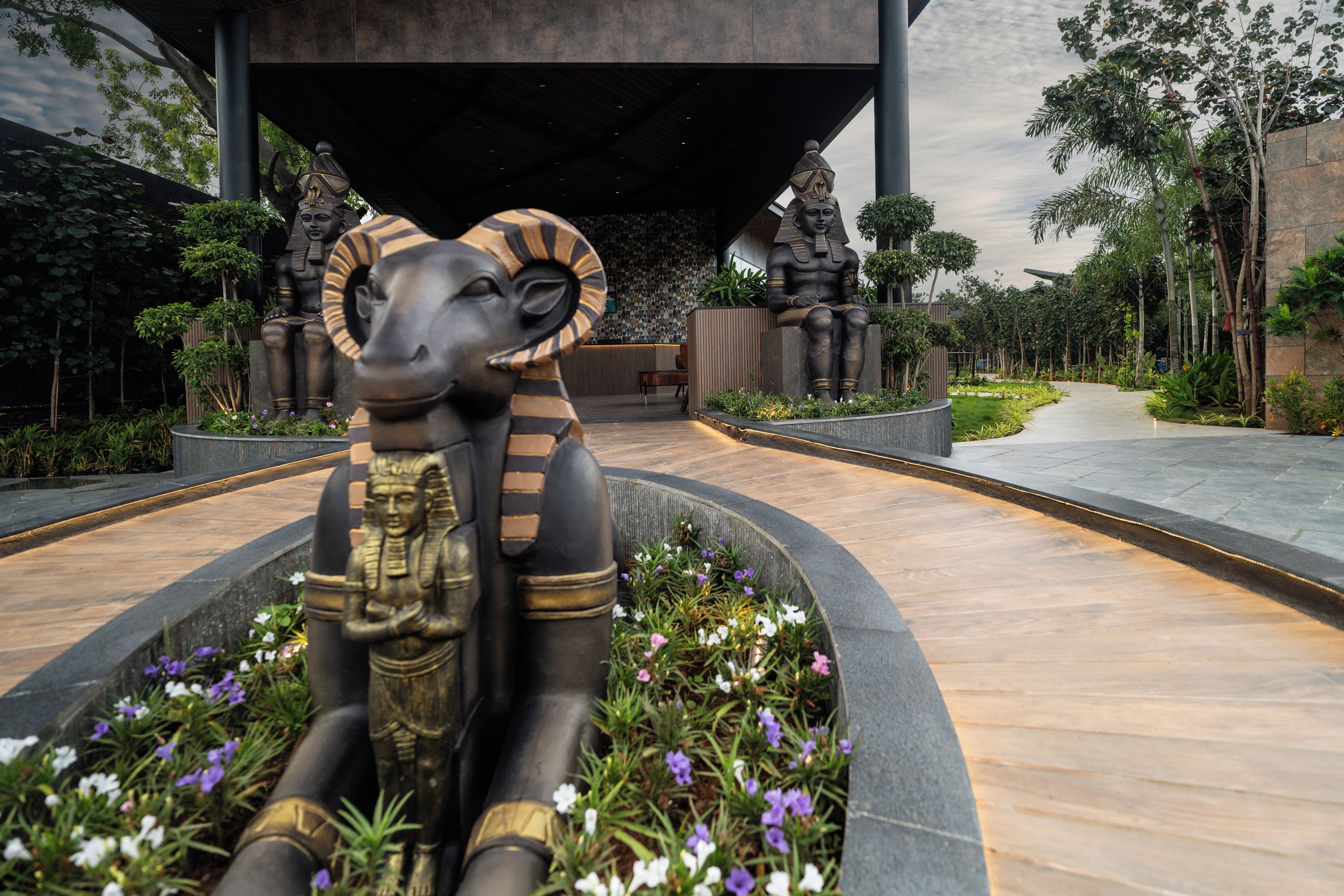 Un sendero conduce a un edificio con una gran estatua de una figura egipcia.