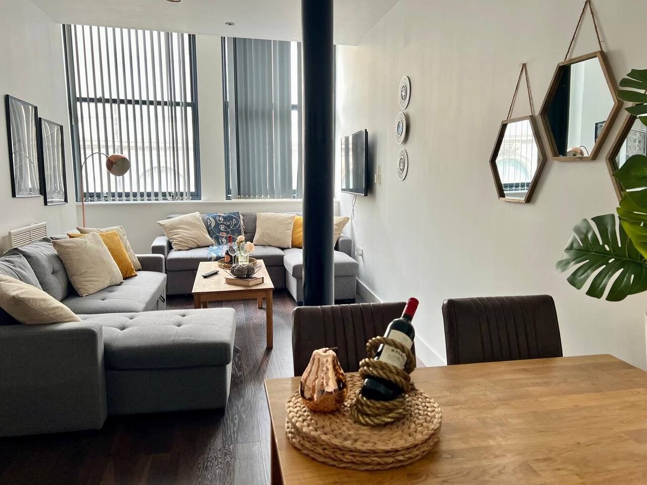 A modern living room with a sofa, coffee table, and a dining table with a bottle and decorative item.