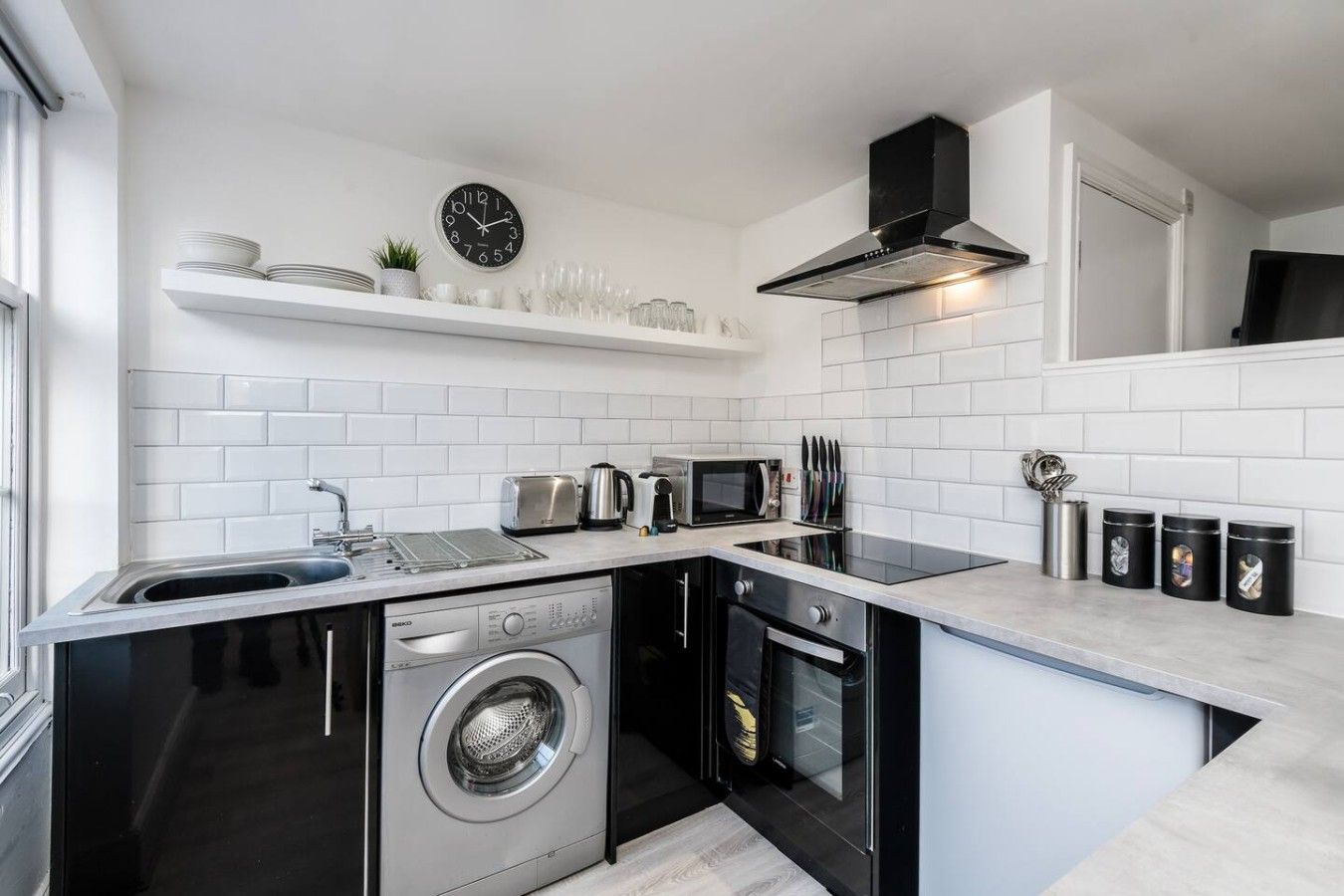 A compact kitchen with a washing machine, a microwave, and a toaster.