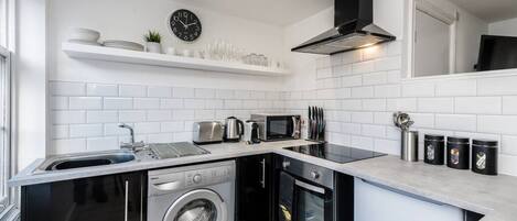 A compact kitchen with a washing machine, a microwave, and a toaster.
