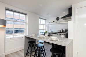 A modern kitchen with a central island, bar stools, and a view of the city. - Jude`s Place 3- 1 bed apt/ 1 sofabed sleeps 4 (Merseyside)