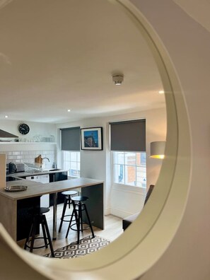 A modern kitchen with a central island, bar stools, and a view through a window. - Jude`s Place 3- 1 bed apt/ 1 sofabed sleeps 4 (Merseyside)