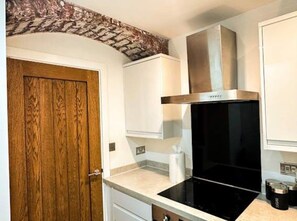 A kitchen with a wooden door, white cabinets, a black stove, and a stainless steel range hood. - Mathew Street - City 1 BDR apt sleeps 6 (Merseyside)