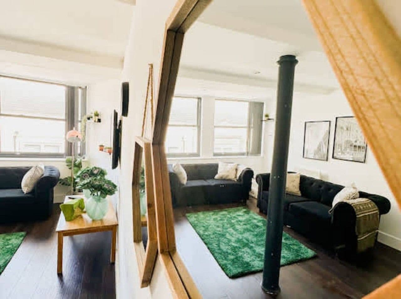 A modern living room with a green rug, two sofas, a coffee table, and a painting on the wall.