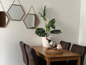 A dining table with a potted plant, a wine bottle, and a candle. - City centre 2 BDR Sleeps 8 (Merseyside)