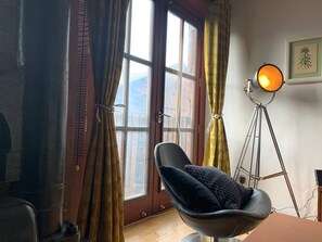 A room with a black chair, a floor lamp, and a window with curtains. - Boss Places converted warehouse-Mathew St. 2 bed (Merseyside)